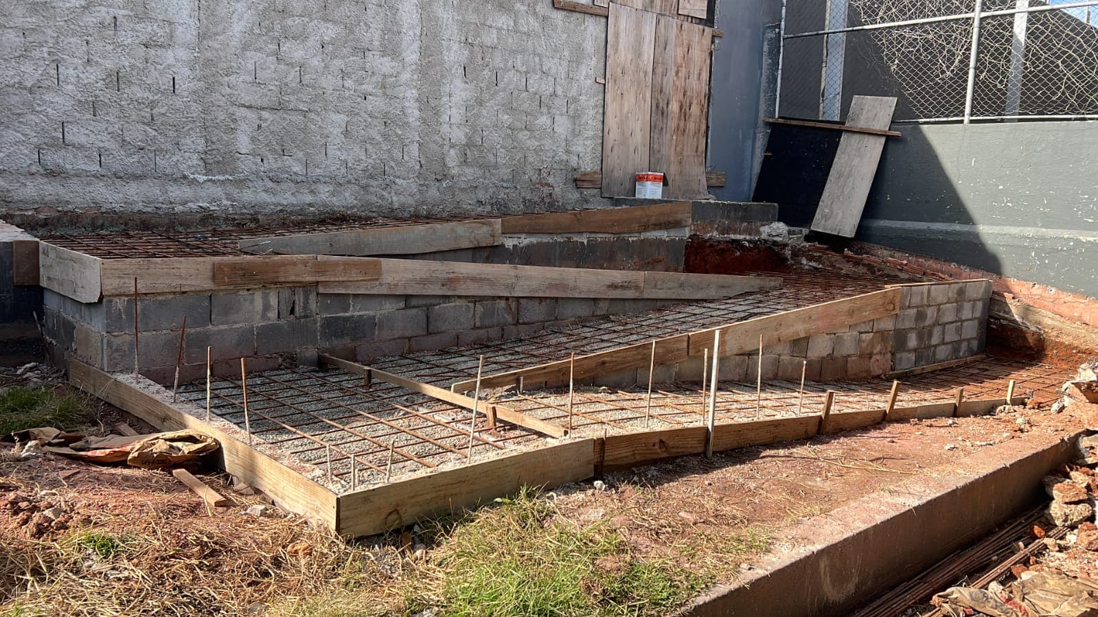 Estrutura de rampa em obra com armação metálica e alvenaria em andamento.