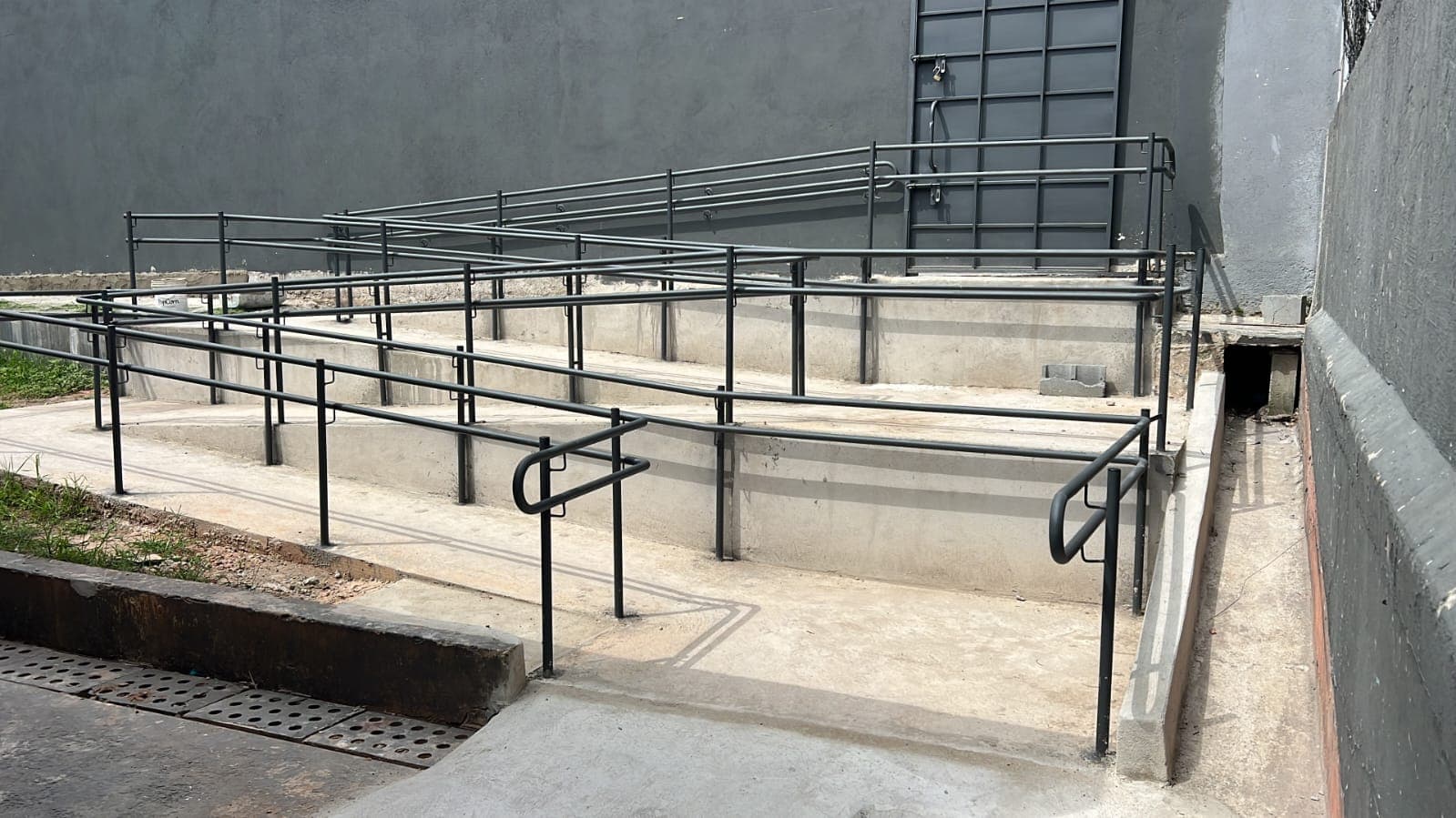 Rampas e guarda-corpos em obra com estrutura metálica e alvenaria em andamento.