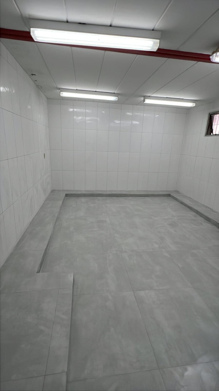 Área interna com piso preparado e revestimento em execução.