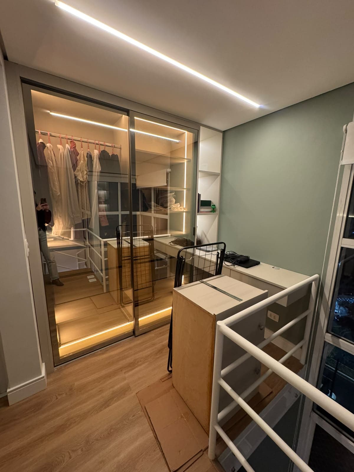 Closet planejado com armários, prateleiras e iluminação integrada.